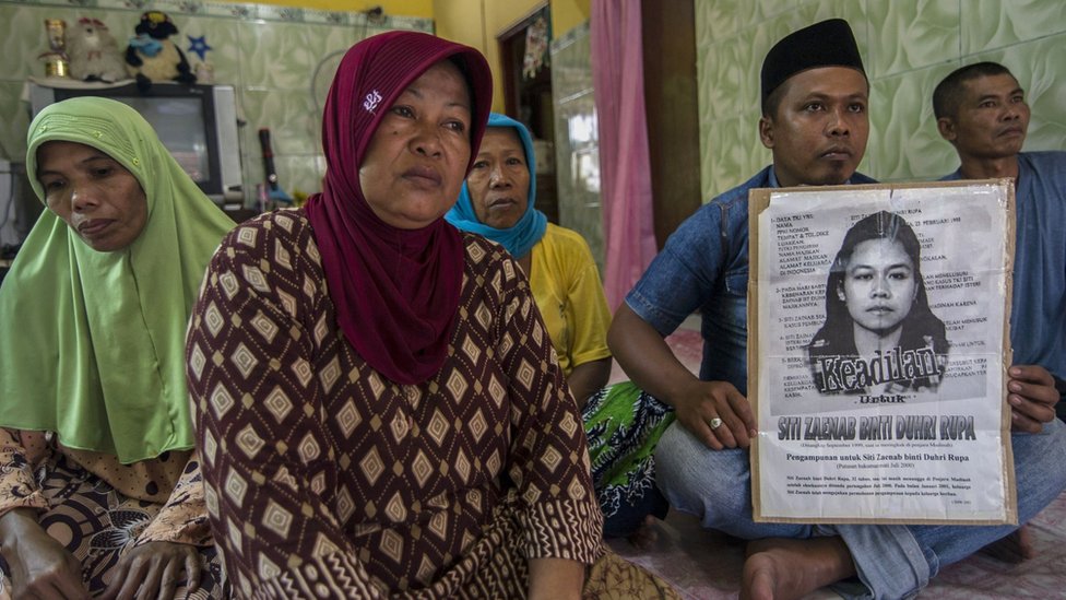 Члены семьи обезглавленной индонезийской горничной Сити Зайнаб держат плакат (R) с ее портретом в их семейном доме в Бангкалане, провинция Восточная Ява, 15 апреля 2015 года