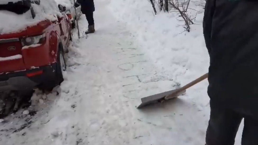 Скриншот из видео, на котором московские муниципальные работники соскребают с тротуара название «Навальный»