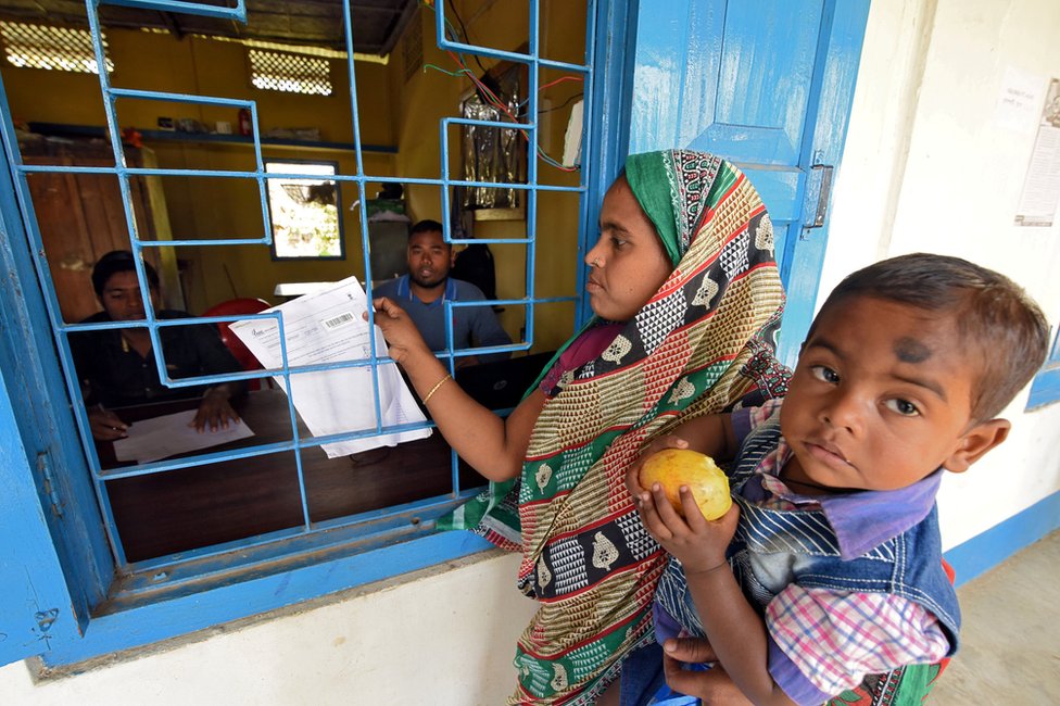 Женщина с сыном на руках приезжает проверить свое имя в предварительном списке центра Национального реестра граждан (NRC) в Чандамари, Ассам.