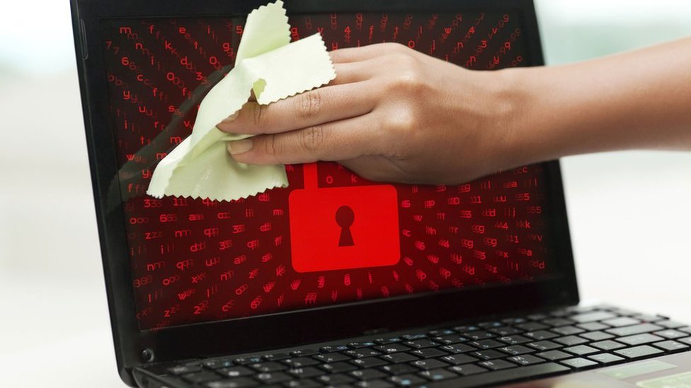 Составное изображение показывает, как кто-то чистит экран ноутбука, в то время как изображение красного замка отображается на экране