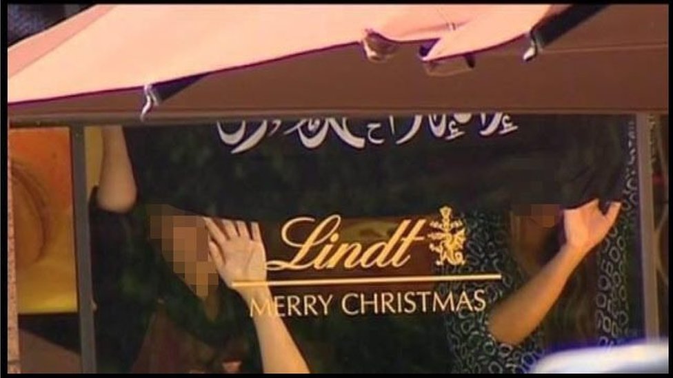 На снимке экрана с канала Channel 7 News, Сидней, предоставленного австралийским Associated Press, показаны две женщины-заложницы в кафе Lindt в Сиднее 15 декабря 2014 г.