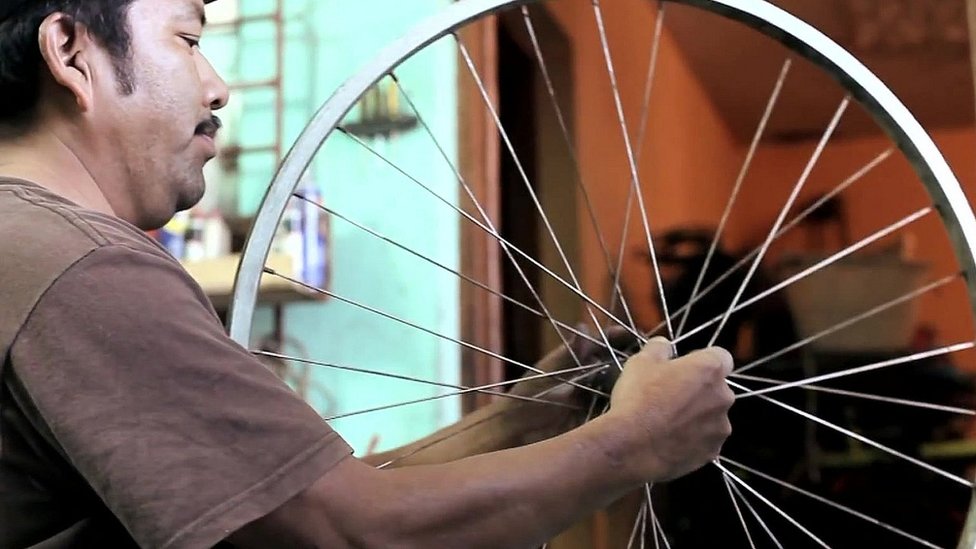 Guatemalan man making a bicycle machine from a second-hand bicycle