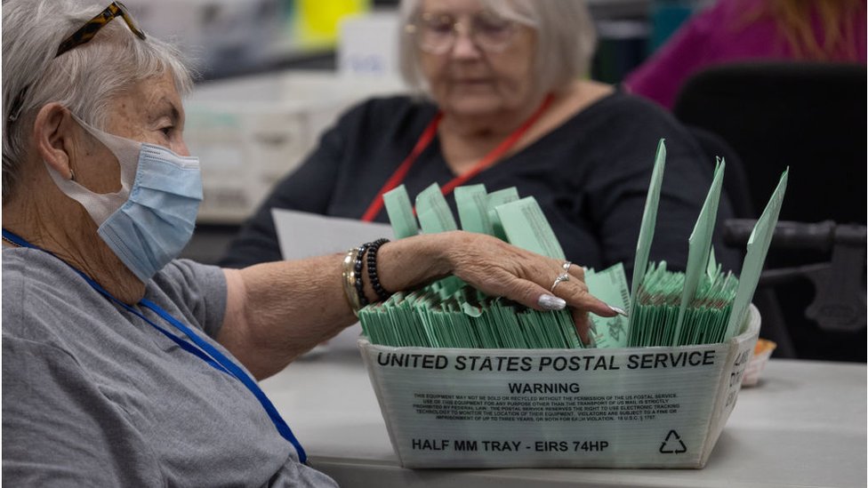 Una mujer espera para votar decenas de votos enviados por correo.