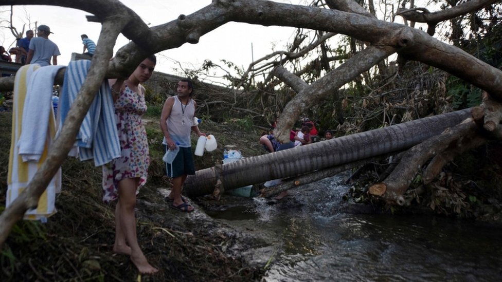 Tras el huracán María hay escasez de agua, alimentos y medicina en Puerto Rico. Una familia se abastece de agua en una quebrada