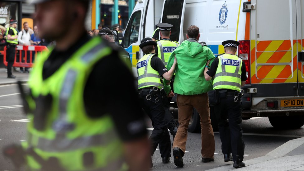 Полицейские уводят протестующего на Лотиан-роуд в Эдинбурге во время демонстрации активистов по борьбе с изменением климата