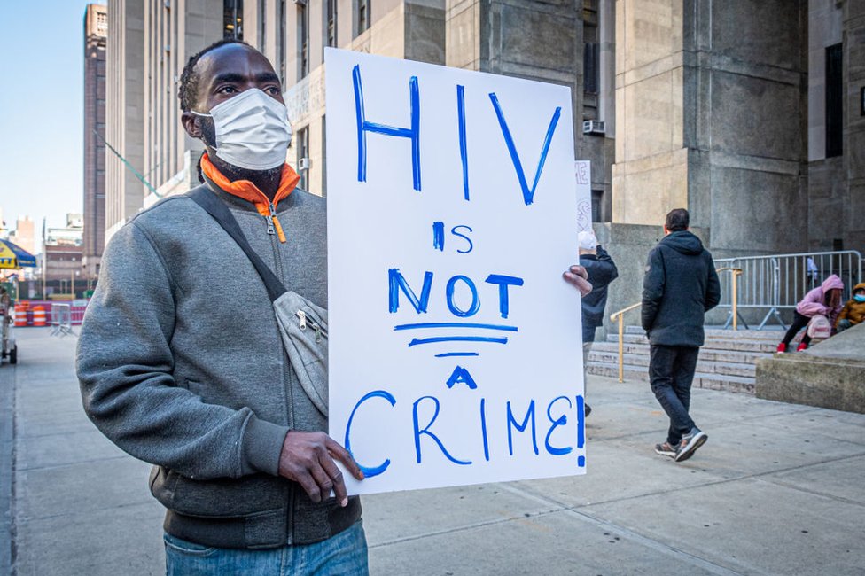 Un hombre sostiene una pancarta durante una protesta organizada por el AIDS Coalition To Unleash Power (ACT UP), Housing Works y GMHC afuera de la oficina del fiscal del Distrito 1 de Nueva York el 9 de noviembre de 2022.