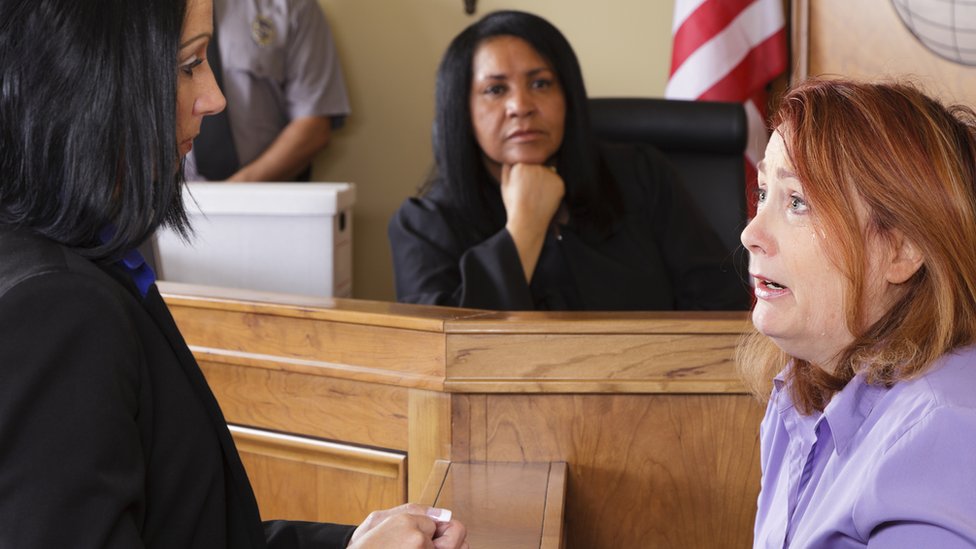 Una juez observa mientras una mujer declara en un juicio