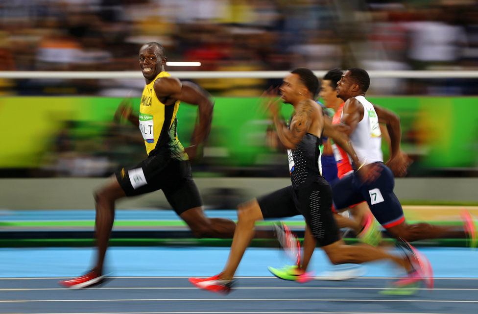 Усэйн Болт с Ямайки улыбается, оглядываясь на своих соперников, выигравших полуфинальный спринт на 100 метров на Олимпийских играх 2016 года в Рио-де-Жанейро, Бразилия