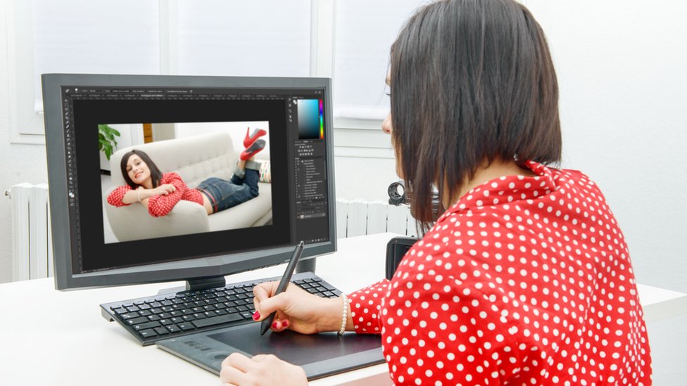 Mujer frente a la computadora editando una fotografía.