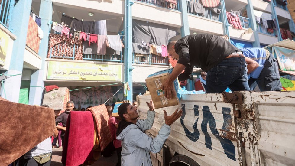 UN workers and volunteers unload aid from a truck in Khan Yunis