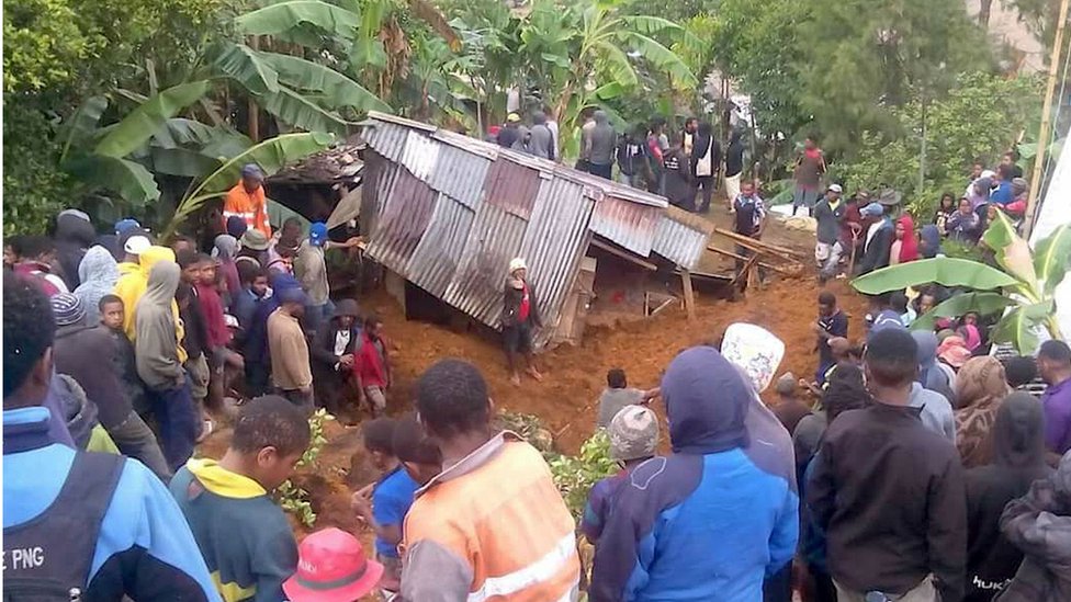Местные жители окружают дом, который был покрыт оползнем в городе Менди после землетрясения в Южном нагорье Папуа-Новой Гвинеи на этом снимке, сделанном 27 февраля 2018 г.