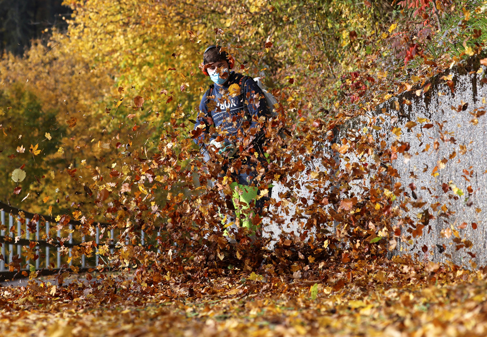 عامل يخلي طريقا للمشاة من أوراق الشجر المتساقط في فصل الخريف بالقرب من ستالينكون في سويسرا.