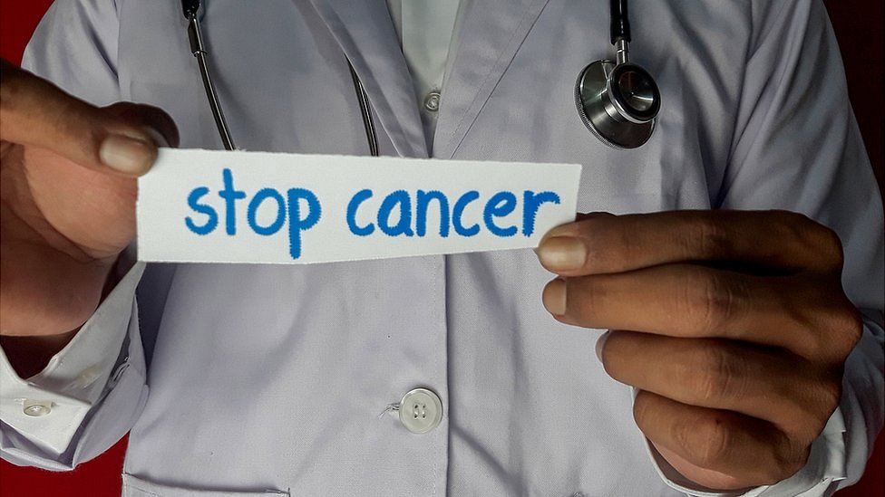 Doctor con papel que dice "Stop cáncer"
