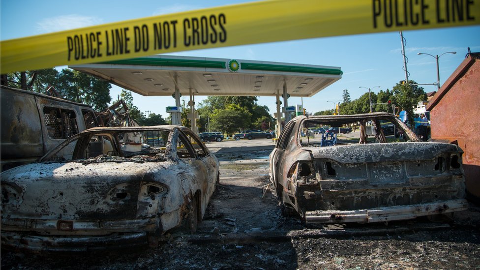 Машины стоят сожженными на участке заправки BP после столкновения участников беспорядков с полицейским управлением Милуоки в знак протеста против офицера, причастного к убийству 14 августа 2016 года в Милуоки, штат Висконсин