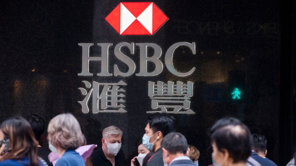 Люди проходят мимо вывески HSBC