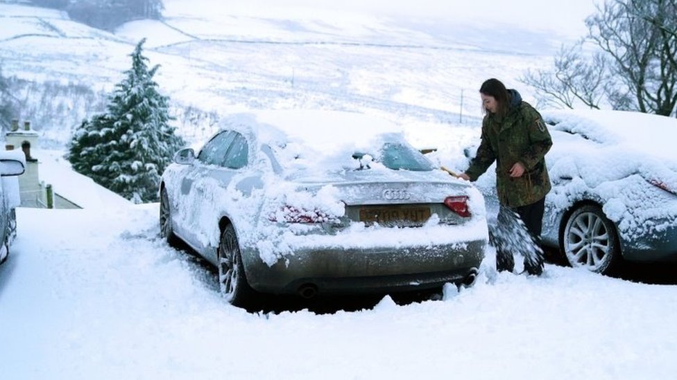 امرأة تزيل الجليد عن سيارتها في كارشيلد في هيكسام