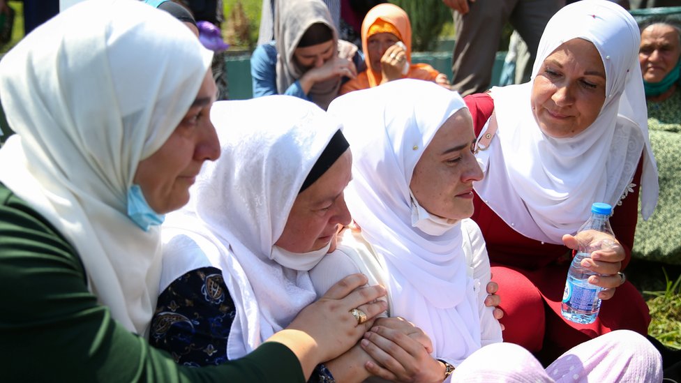 Женщины плачут на кладбище во время массовых похорон в Поточари недалеко от Сребреницы