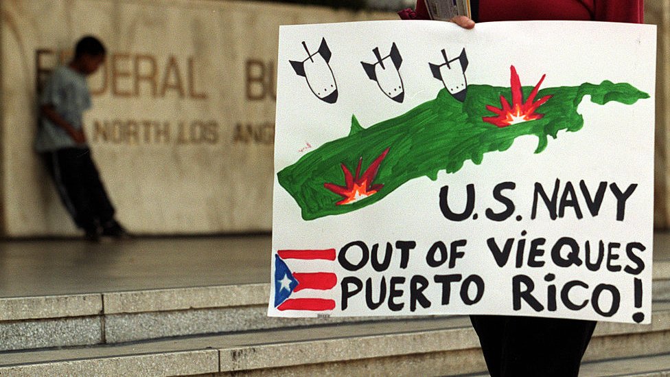 Una persona con un cartel en contra de la Marina en Vieques