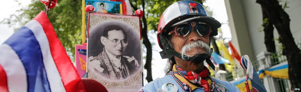 67-летний тайский велосипедист Адд проталкивает свой велосипед мимо фотографии короля Таиланда Пумипона Адульядета перед тем, как принять участие в массовой велосипедной кампании «Велосипед для мамы» в Бангкоке, Таиланд, в воскресенье