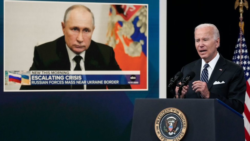 بايدن أثناء تعليقه على اسعار الغاز وتظهر صورة للرئيس بوتين في الخلفية (22 يونيو/حزيران 2022)
