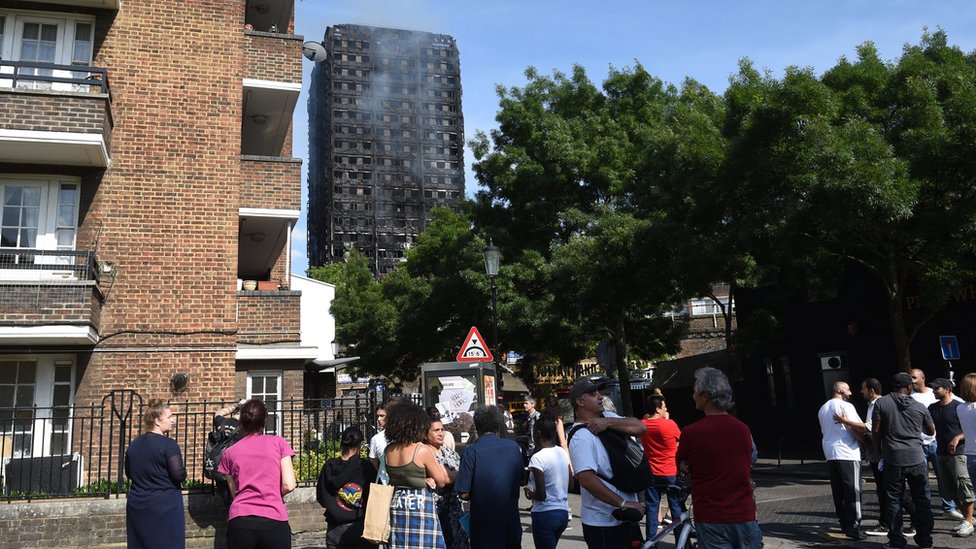 Según algunos testigos, el incendio se propagó en cuestión de minutos por todo el edificio de 24 pisos. Personas miran el edificio quemado