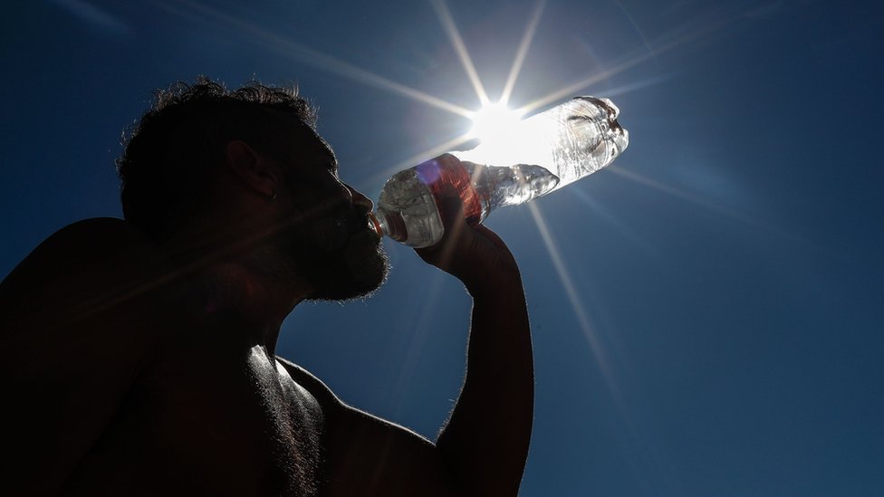 Muškarac pije vodu na Kopakabana plaži u Rio de Žaneiru, Brazil, 19. septembar 2023, tokom toplotnog talasa