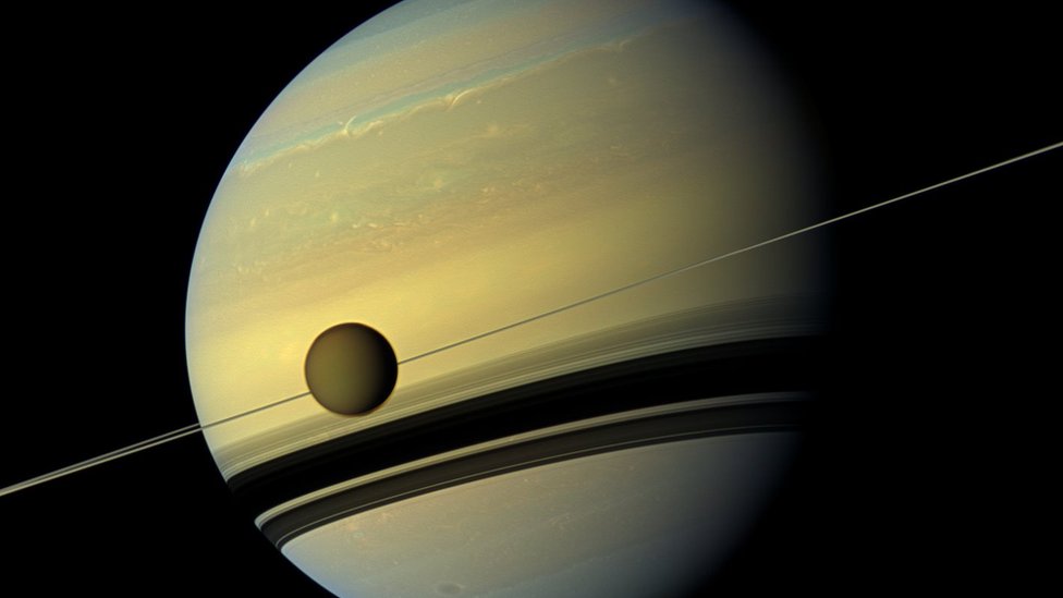 Сатурн и его спутник Титан. Атмосфера Титана невыразительно коричневого цвета.