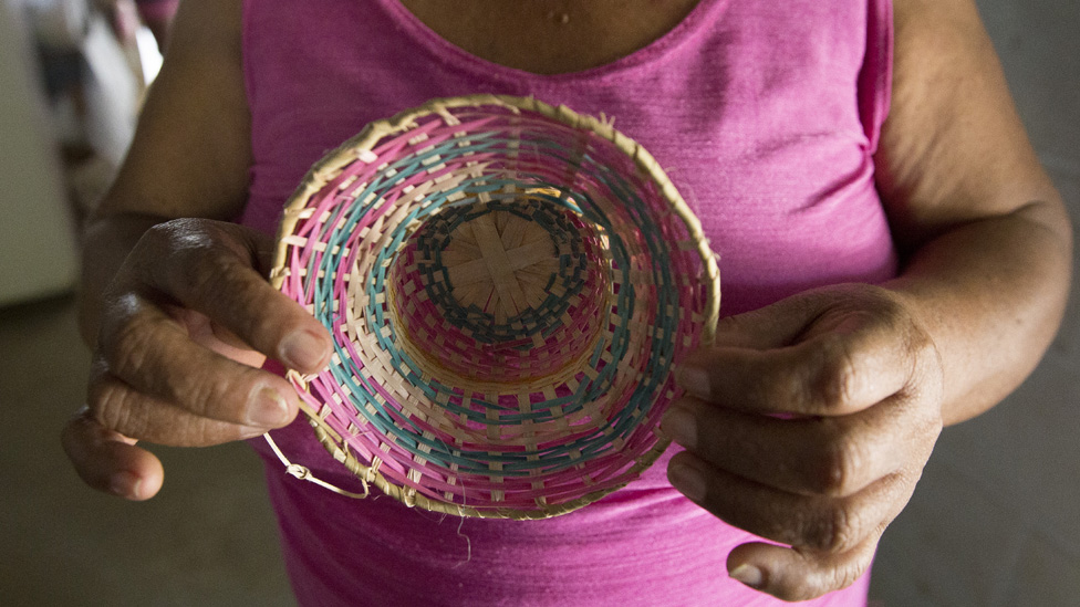 53-летняя Эльвия Баутиста из Кордовы, Колумбия, показывает крошечную шляпку, которую она сделала из волокон растений возле своего дома.