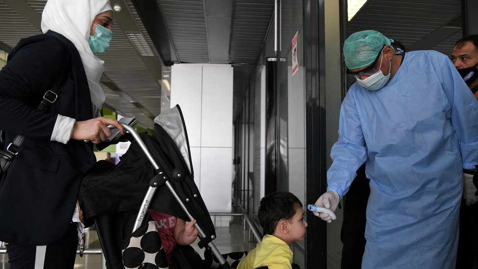 Медицинский работник измеряет температуру ребенка в аэропорту Дамаска 1 октября 2020 года