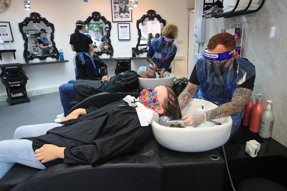 Клиенты моют волосы, поскольку сотрудники носят козырьки в The Salon Leeds