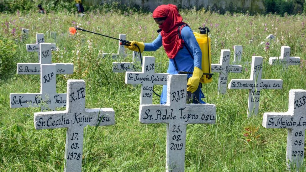 A municipal worker sanitises a Roman Catholic Church graveyard after the burial of Covid-19 coronavirus infected people