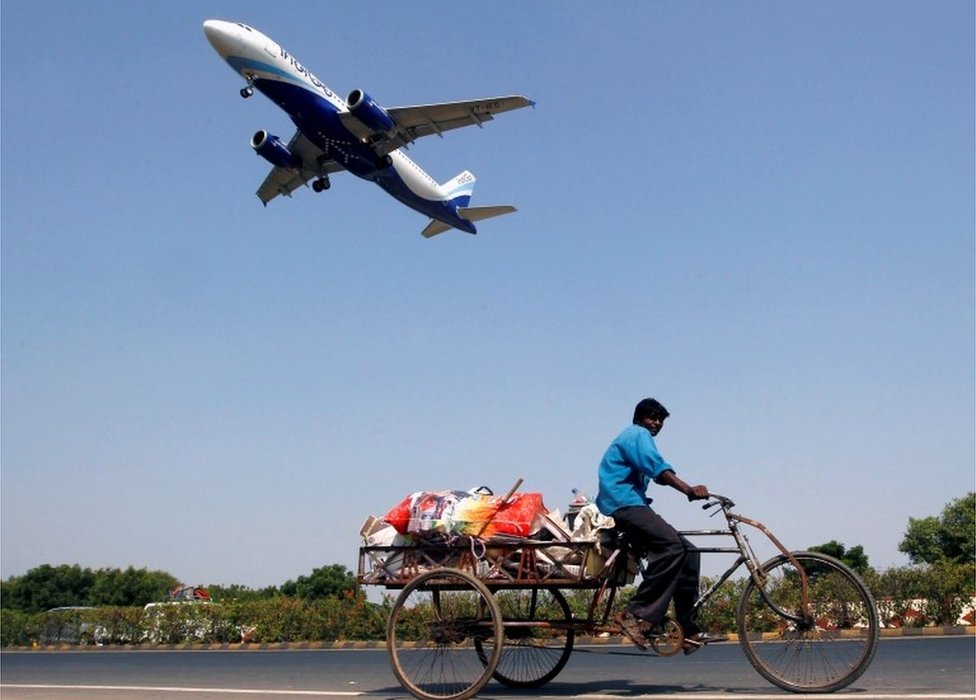 Самолет IndiGo Airlines готовится к посадке, когда мужчина ведет велорикшу в Ахмедабаде, Индия, 26 октября 2015 г.