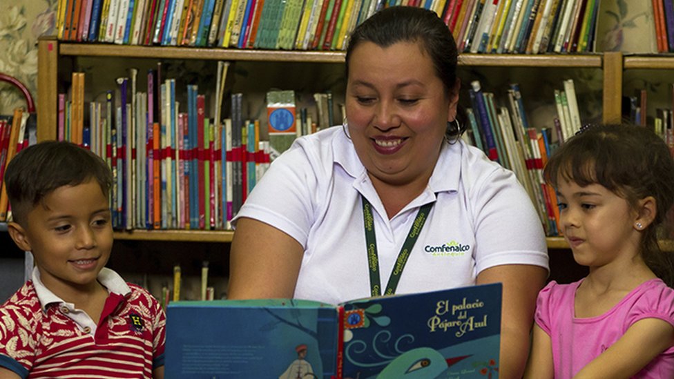 Женщина читает двоим детям в рамках одной из программ, проводимых Confenalco