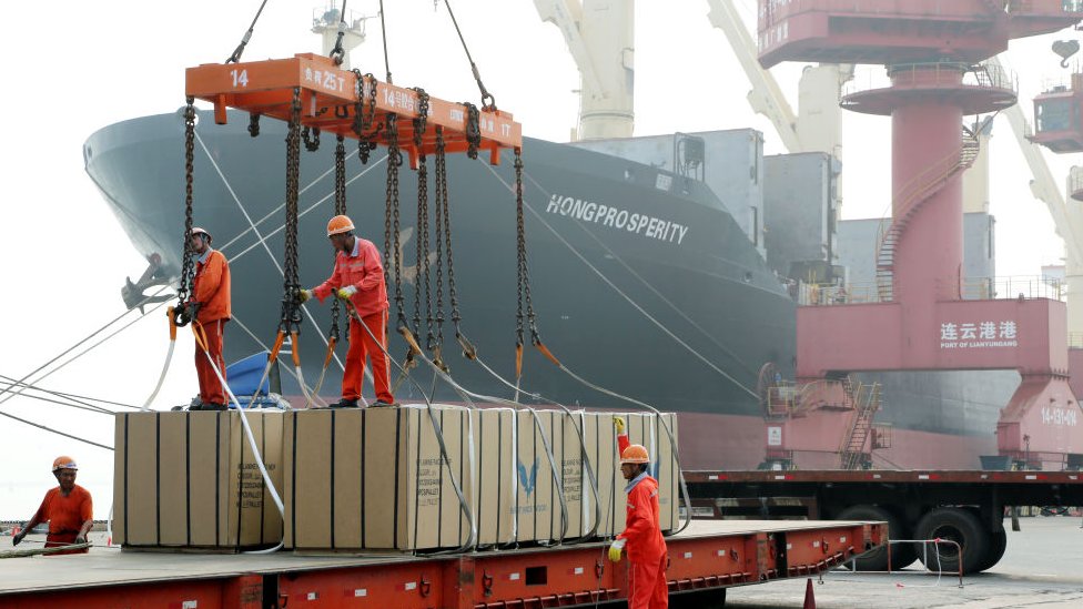 Рабочие загружают ящики на корабль в порту Ляньюньган.
