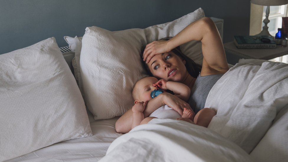 Para algunas personas no hay distinción entre días laborales y fines de semana. Madre despierta con bebé dormido