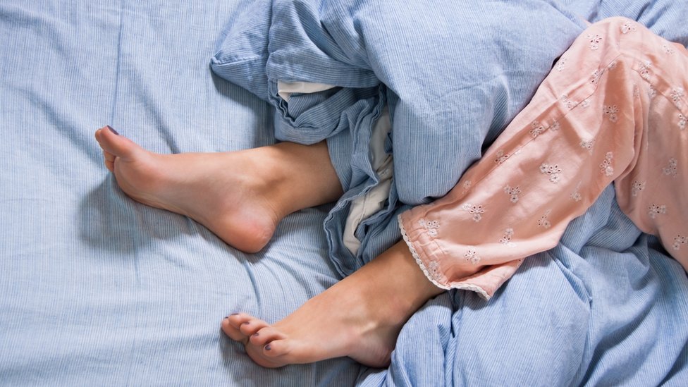 Bare feet of a woman on a blue bed