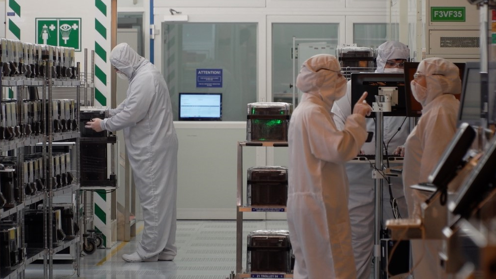 Workers in the microchip factory dressed in protective suits