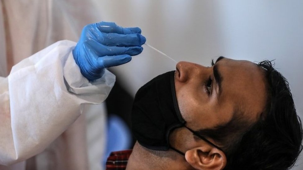 Seorang karyawan India yang bekerja di mal, bereaksi saat petugas kesehatan mengambil sampel usap hidung untuk melakukan tes Antigen Cepat untuk Covid-19 di dalam mal di Mumbai, India