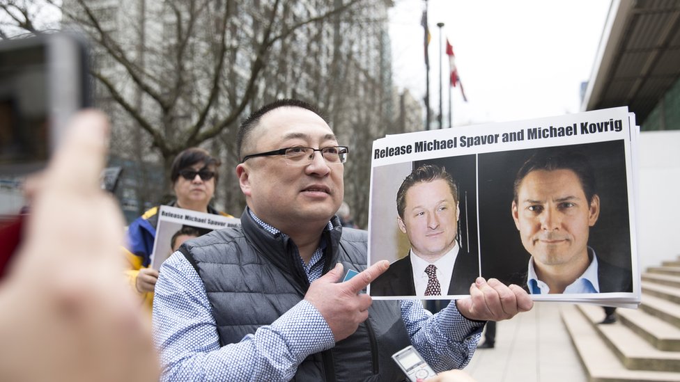Протестующий за демократию в Китае держит фотографии канадцев Майкла Спавора и Майкла Коврига