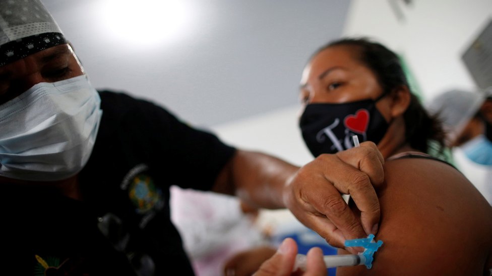 Profissional de saúde aplica vacina contra covid-19 em mulher em Manaus