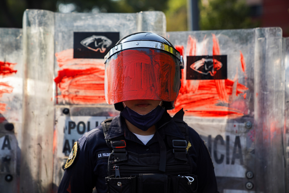 A riot police officer with her helmet visor painted red