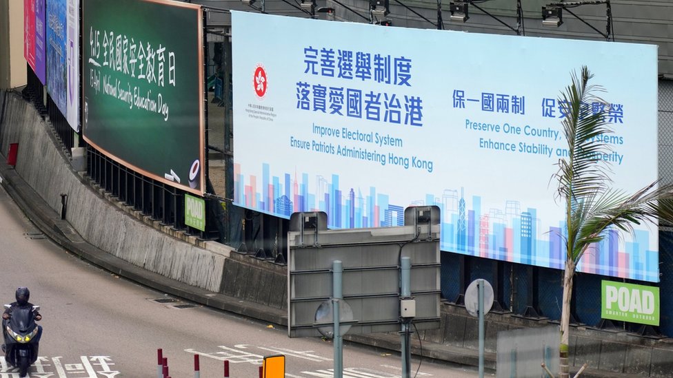 A motorcyclist rides past a billboard reading 'Improve Electoral System, Ensure Administering Hong Kong, Preserve One Country, Two System, Enhance Stability and Prosperity' in the street on March 31, 2021 in Hong Kong, China