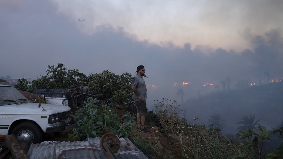 Un hombre mira desde el cerro las columnas de humo que se extienden sobre la ciudad