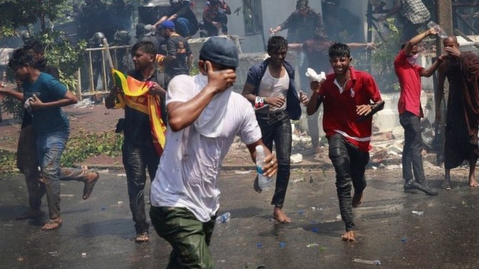 Protesters run for cover as police use tear gas to disperse them outside the Sri Lankan prime minister's office in Colombo, Sri Lanka
