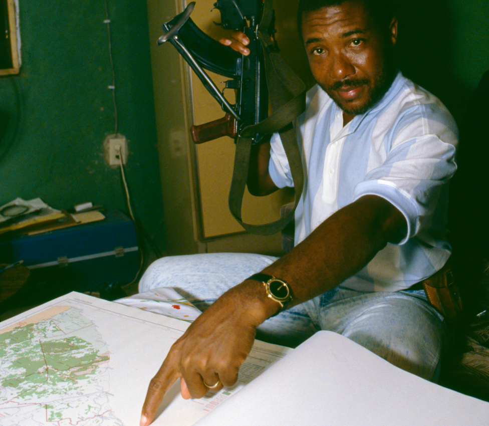 Чарльз Тейлор держит пистолет и указывает на карту в 1989 году, когда он начал восстание в Либерии