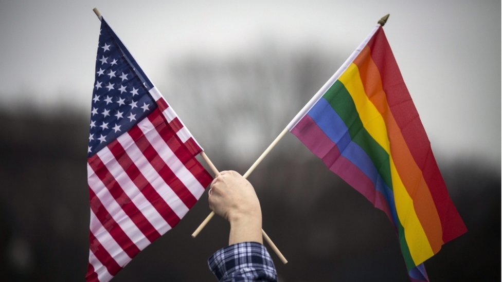 شخص يحمل العلم الأمريكي وعلم المثليين جنسيا