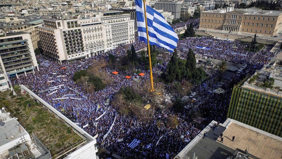 Люди держат греческие флаги, демонстрируя, что они призывают правительство не идти на компромисс в разгорающейся череде имен с соседней Македонией, на площади Синтагма в Афинах, 4 февраля 2018 г.