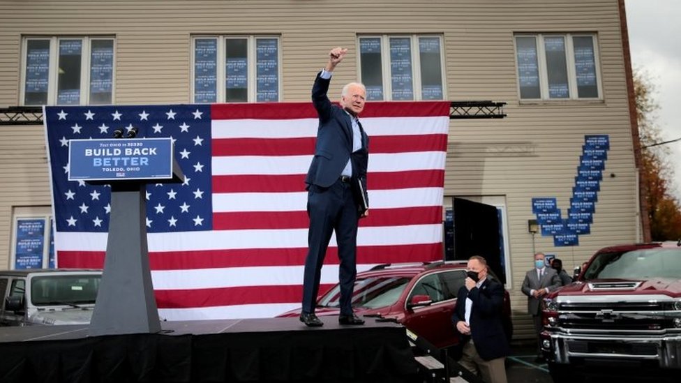 US Democratic presidential candidate Joe Biden raises his arm during a drive-in campaign event in Toledo, Ohio on 12 October 2020