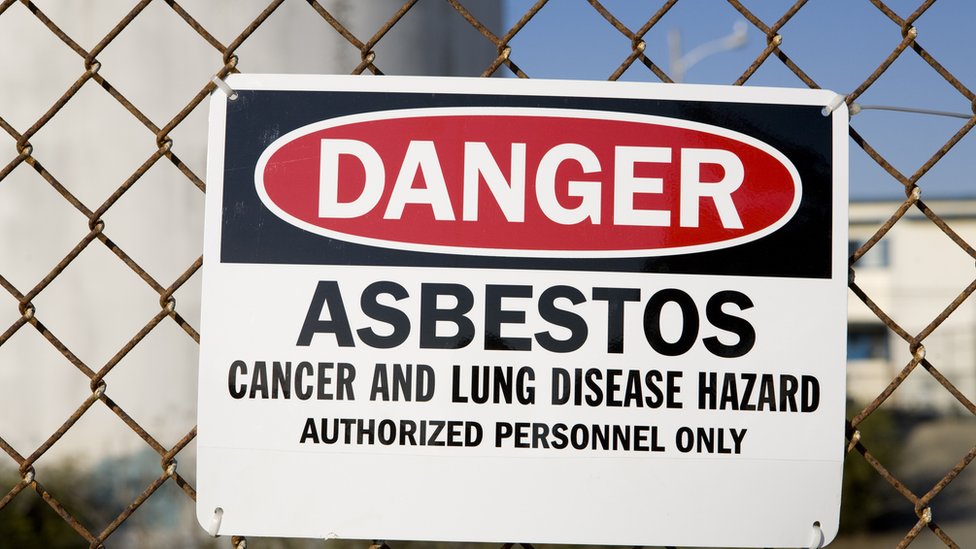 A sign warns of asbestos removal dangers