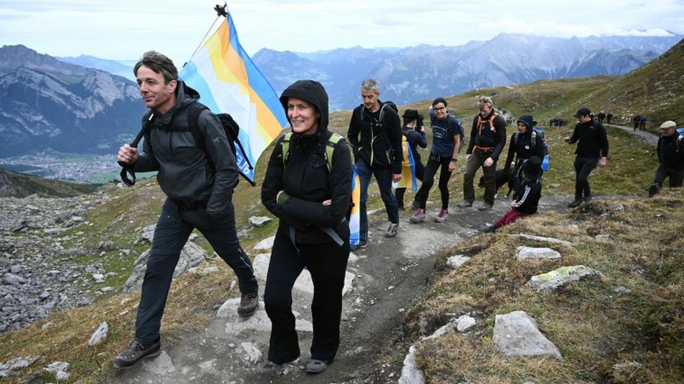 Люди принимают участие в поминальном марше по леднику, потерянному в результате глобального потепления